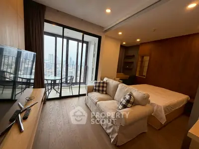 Modern studio apartment with cozy living area and balcony overlooking cityscape