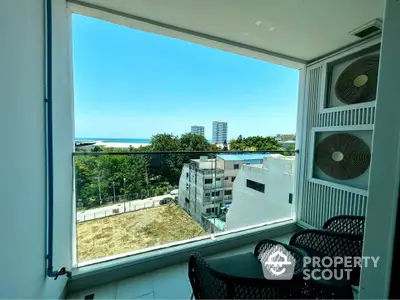 Stunning balcony view with modern seating and ocean backdrop in high-rise apartment.