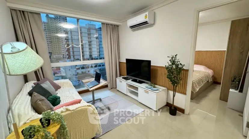 Modern living room with city view, cozy decor, and adjacent bedroom in urban apartment.