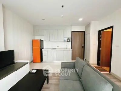 Modern living room with open kitchen, featuring sleek furniture and bright decor.