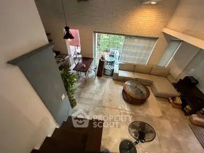 Spacious living room with high ceiling and modern decor, featuring large windows and cozy seating area.