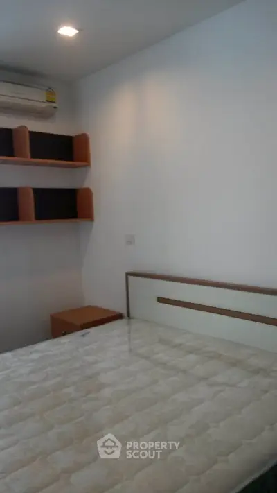 Cozy bedroom with modern design, featuring built-in shelves and air conditioning.