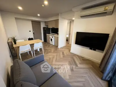 Modern living room with open kitchen, featuring sleek appliances and stylish decor.