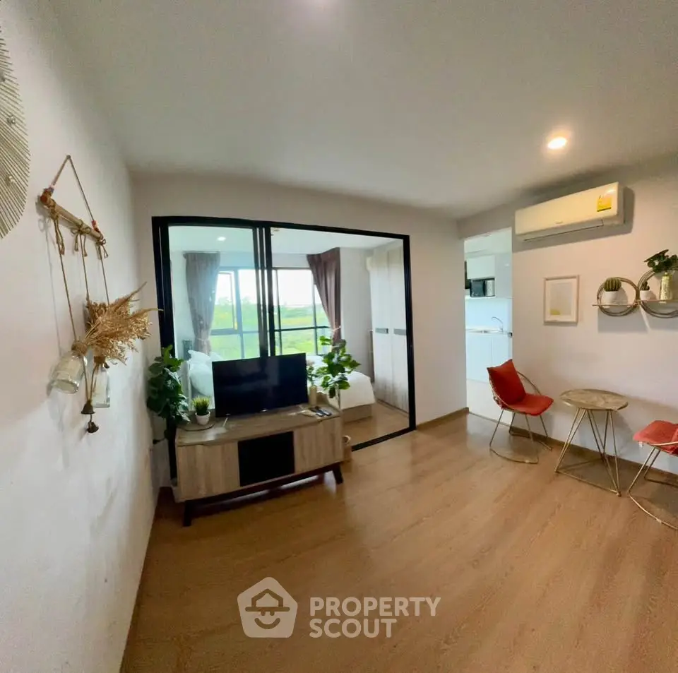 Modern living room with stylish decor and open view to bedroom, featuring wooden flooring and cozy seating area.