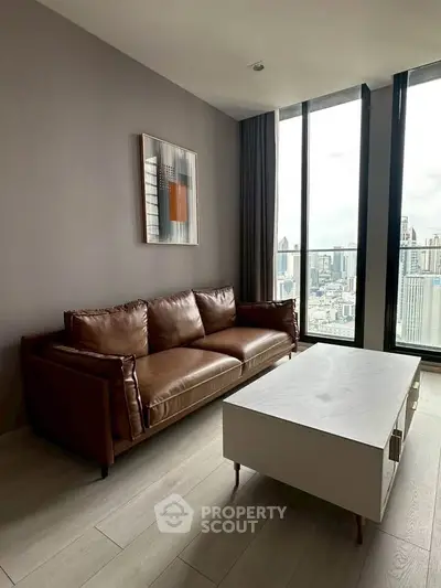 Stylish living room with leather sofa and city view from large windows.