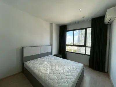 Spacious bedroom with large window offering city views, featuring a comfortable bed and modern decor.