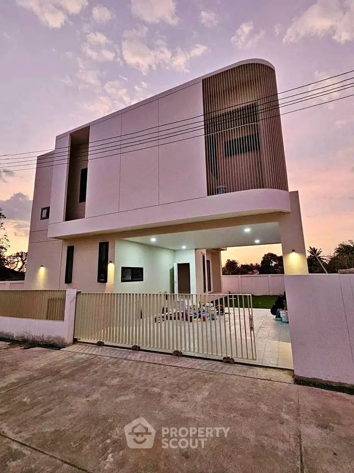 Modern two-story house with sleek design and spacious driveway at sunset.