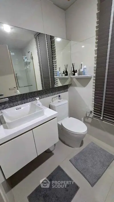 Modern bathroom with sleek fixtures and large mirror in a contemporary home.