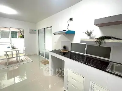 Modern kitchen with sleek design and dining area, featuring open layout and natural light.