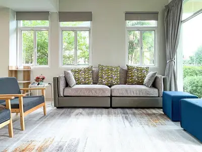 Spacious living room with modern sofa and large windows offering garden views.