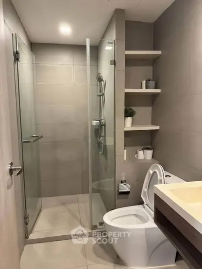 Modern bathroom with glass shower and sleek fixtures in contemporary apartment.
