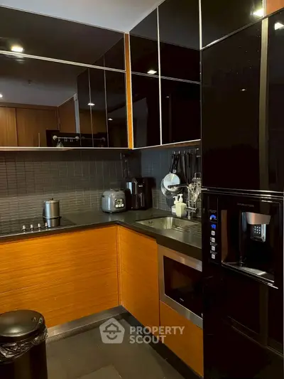 Modern kitchen with sleek black appliances and wooden cabinetry, featuring a built-in oven and stylish backsplash.