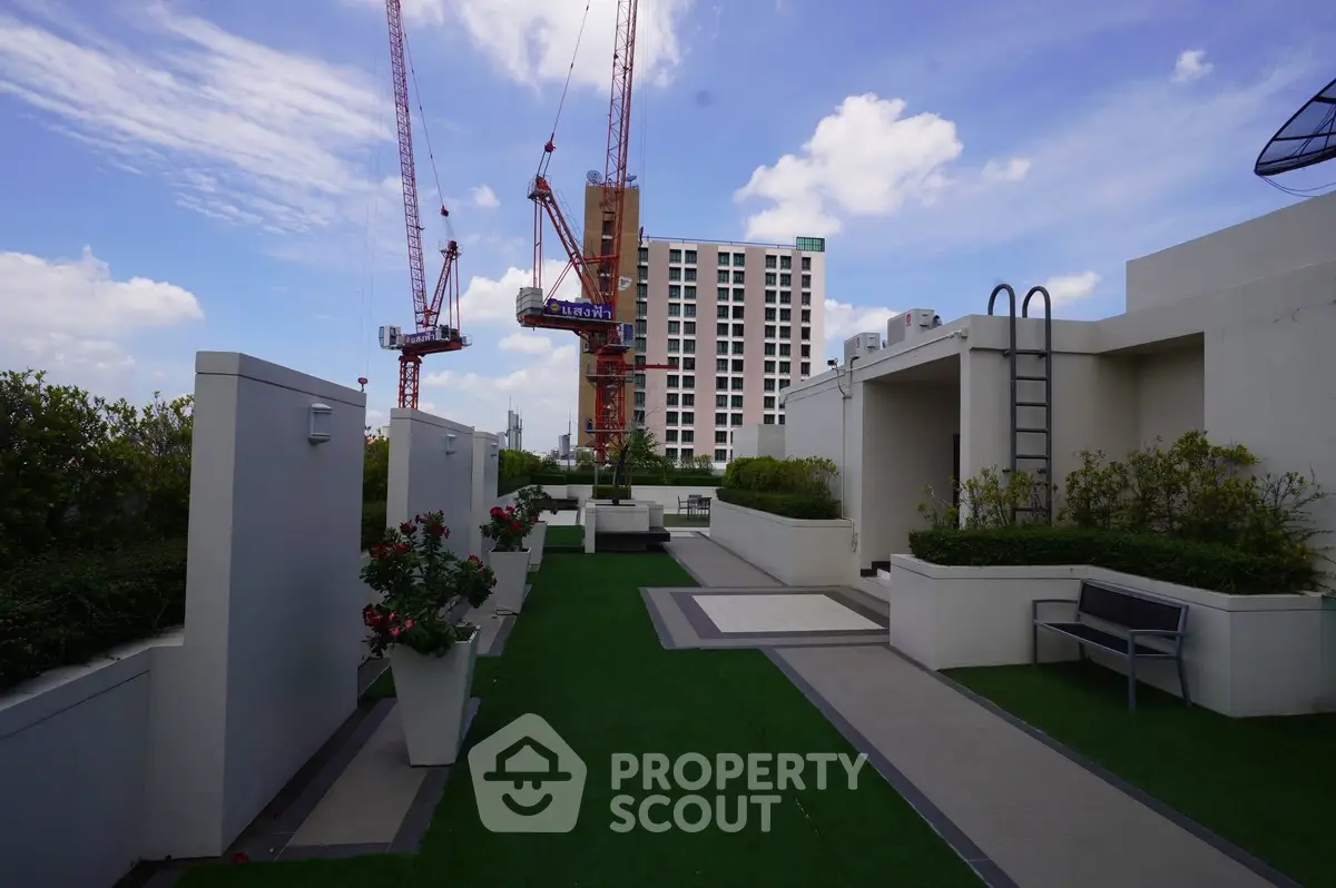 Modern rooftop garden with city view and construction cranes in the background.