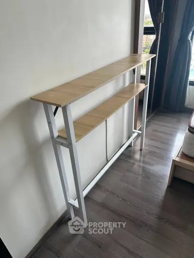 Modern minimalist wooden shelf in a bright room with large window and hardwood floors.