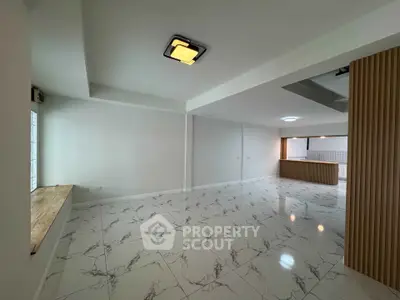 Spacious modern living room with marble flooring and open layout kitchen.