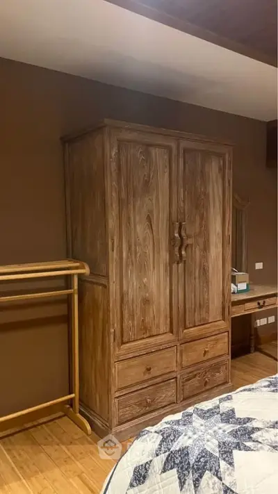 Cozy bedroom with wooden wardrobe and quilted bedspread