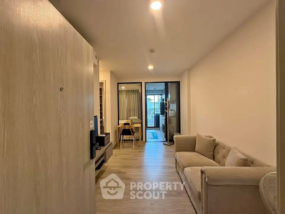 Modern living room with cozy sofa and open layout leading to balcony