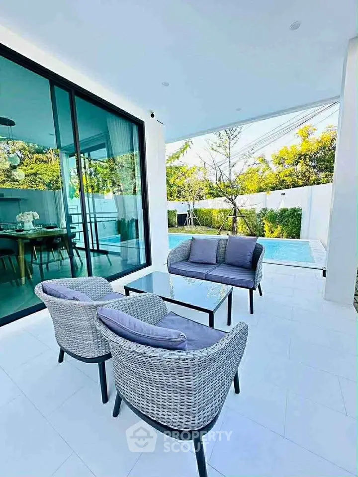 Luxurious patio with modern furniture overlooking a private pool and lush garden.