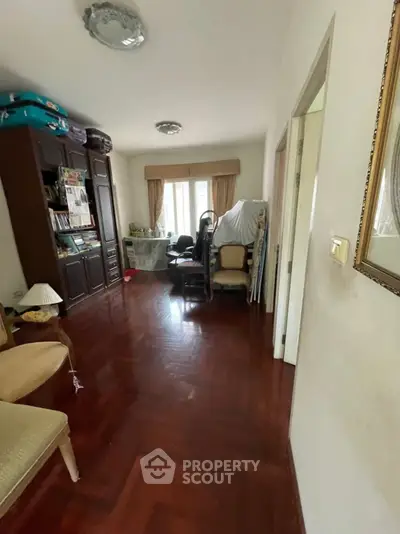 Spacious living room with wooden flooring and ample natural light, featuring elegant furniture and a cozy ambiance.