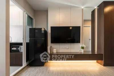Modern living room with sleek TV setup and adjacent kitchen area in stylish apartment.