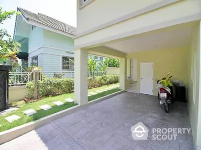 Spacious covered parking area in modern residential property with lush garden view.