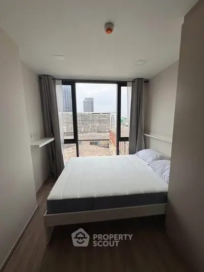 Modern bedroom with large window offering city view, minimalist design and natural light.