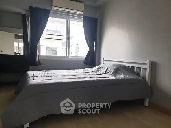 Cozy bedroom with modern decor and large window for natural light.