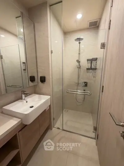 Modern bathroom with glass shower enclosure and sleek vanity in contemporary apartment.