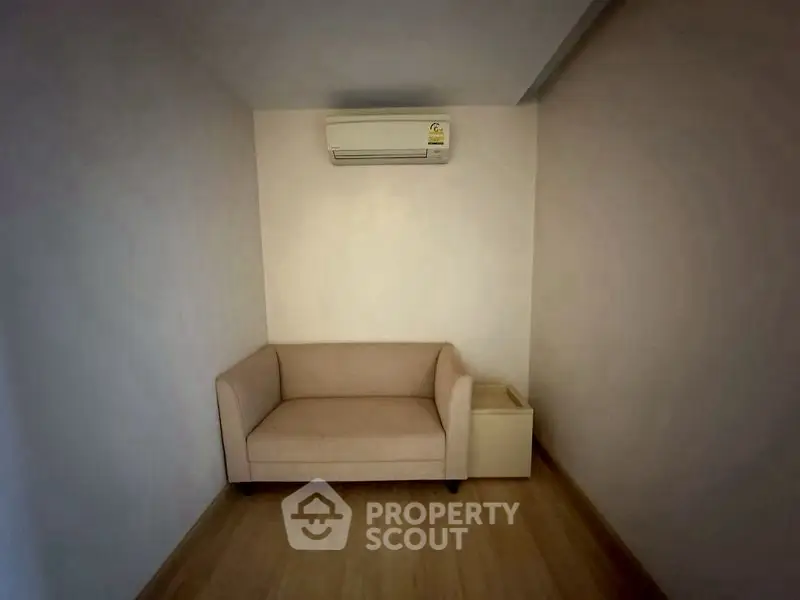 Cozy small living area with beige sofa and air conditioning unit, perfect for compact spaces.