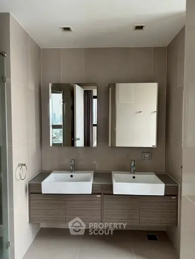 Modern bathroom with dual sinks and sleek cabinetry in a contemporary apartment.