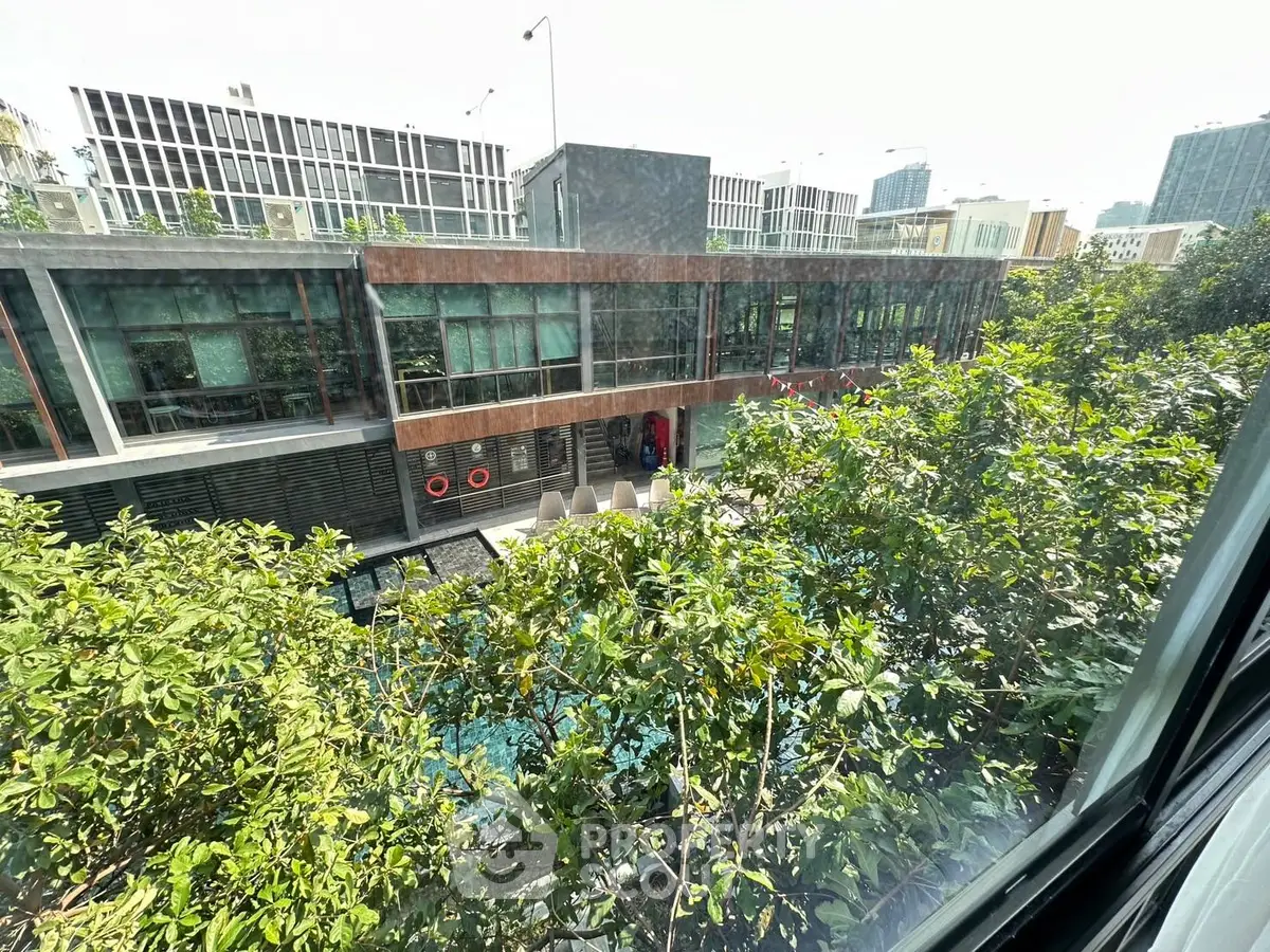 Modern building exterior with lush greenery and pool view from window.