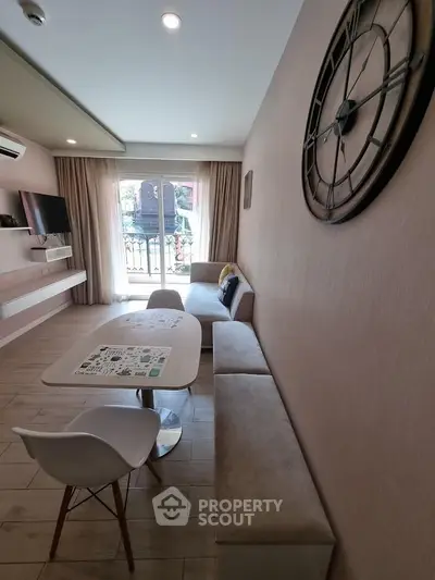 Modern living room with stylish decor and large wall clock, featuring a cozy seating area and natural light.