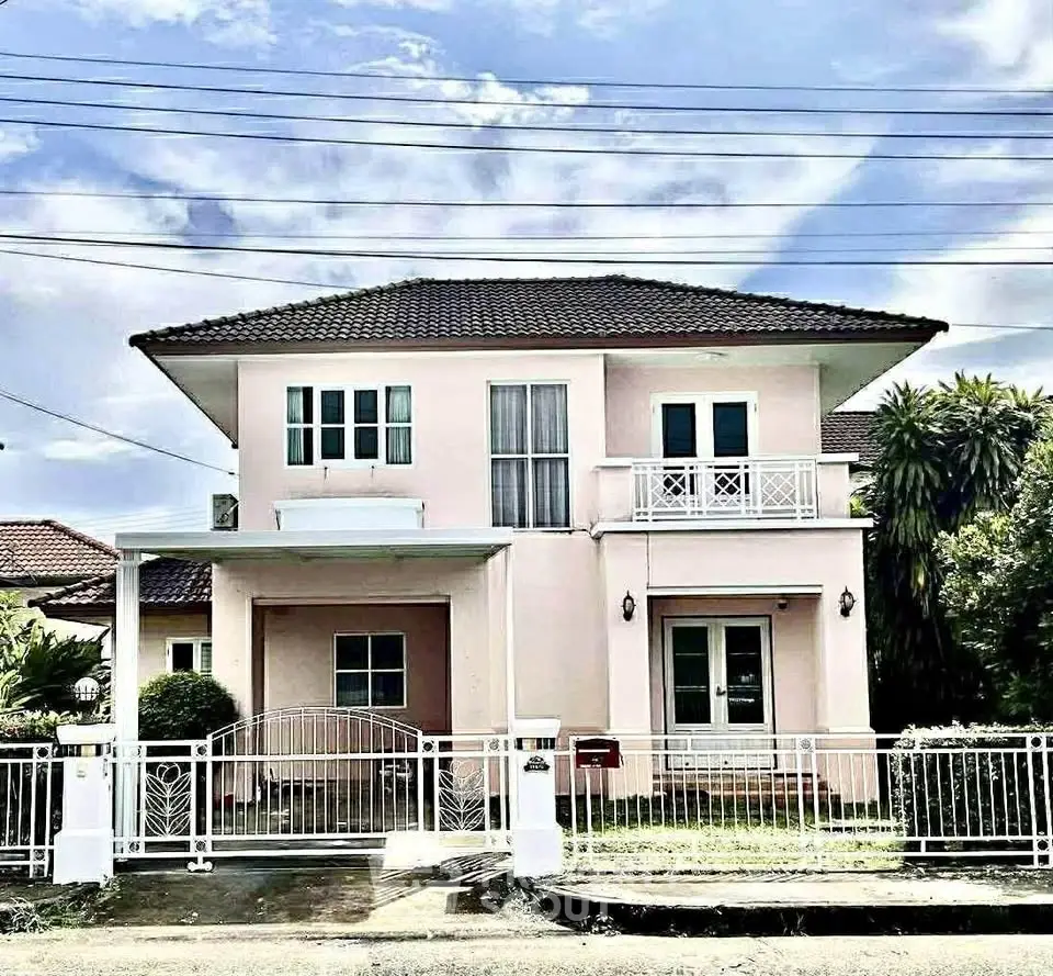 Charming two-story house with balcony and lush garden in serene neighborhood.