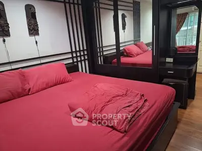 Luxurious bedroom with red bedding and mirrored wardrobe in modern apartment.