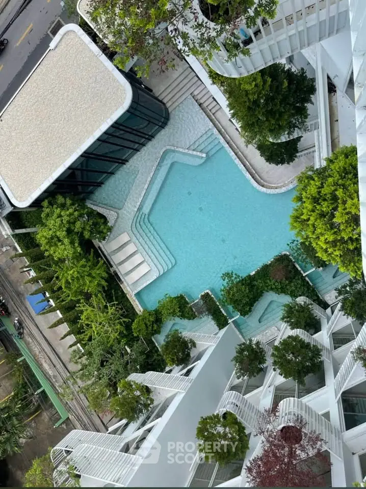 Stunning aerial view of modern building with luxurious pool and lush greenery, perfect for urban living.