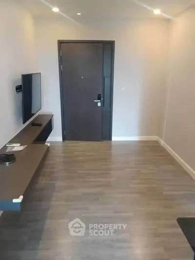 Modern minimalist apartment entrance with sleek wooden flooring and wall-mounted TV.