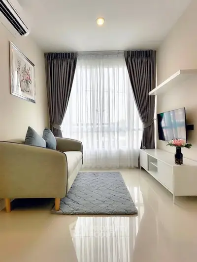 Modern living room with elegant decor, featuring a cozy sofa, stylish curtains, and a sleek TV setup.