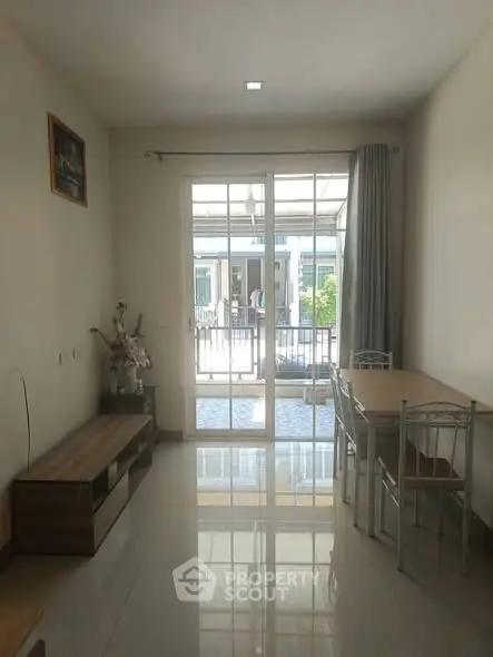 Bright dining area with glass doors leading to a balcony, featuring modern furniture and natural light.