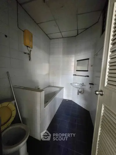 Compact bathroom with bathtub and sink, featuring tiled walls and floor.