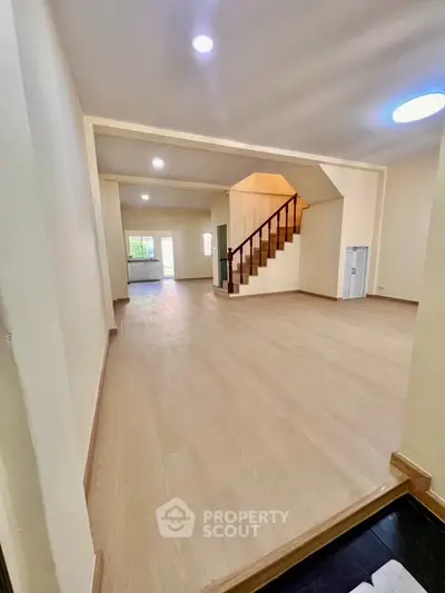 Spacious open-plan living area with wooden flooring and staircase, ideal for modern family living.