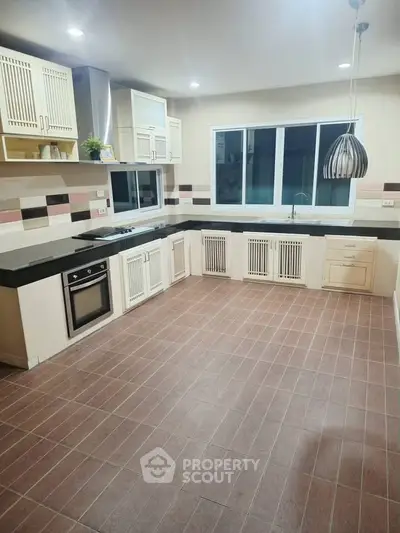 Spacious modern kitchen with sleek countertops and built-in oven, perfect for culinary enthusiasts.