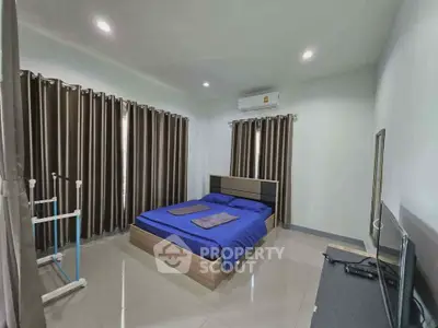 Spacious bedroom with modern furnishings and ample natural light, featuring sleek tile flooring and air conditioning.