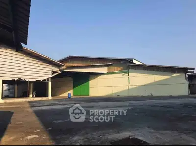 Spacious industrial warehouse exterior with ample open space and clear blue sky.