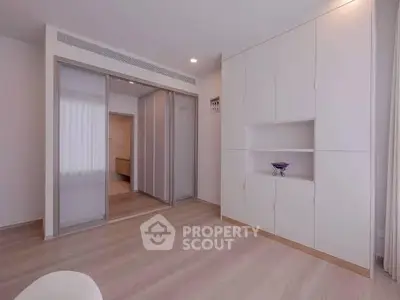 Spacious modern bedroom with sleek built-in storage and sliding closet doors.