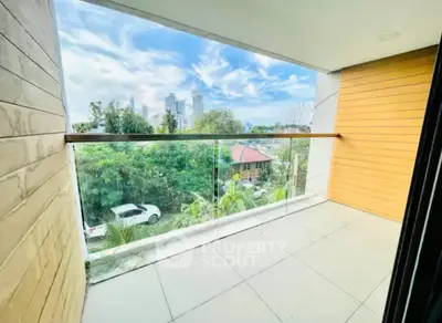 Spacious balcony with glass railing offering a stunning city view, perfect for relaxation.
