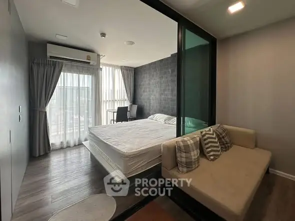 Modern bedroom with glass partition and cozy seating area in stylish apartment