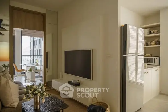 Modern living room with sleek TV setup and adjacent kitchen area in a stylish apartment.