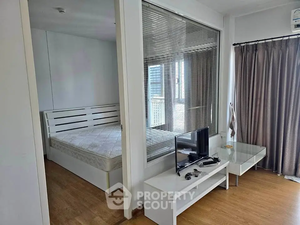 Modern apartment with open layout featuring bedroom and living area, sleek furniture, and natural light.