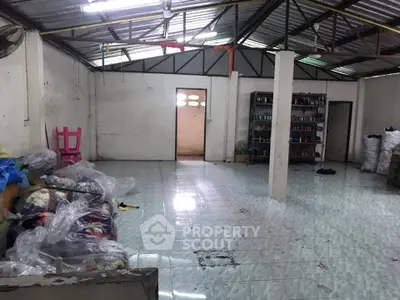 Spacious industrial-style room with tiled floor and metal roof, ideal for storage or workshop use.