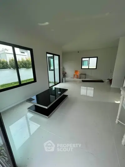 Spacious modern living room with sleek black coffee table and large windows.